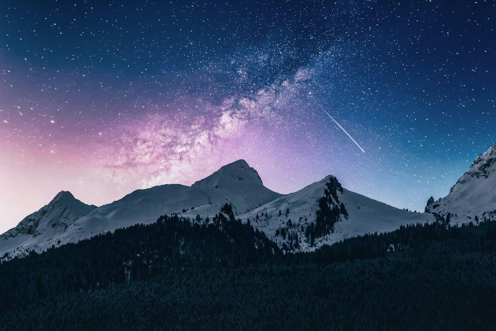 Starry night sky over snowy mountain peaks
